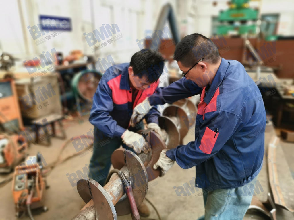 法鋼技術人員正在對耐磨螺旋輸送部件進行組裝和焊接